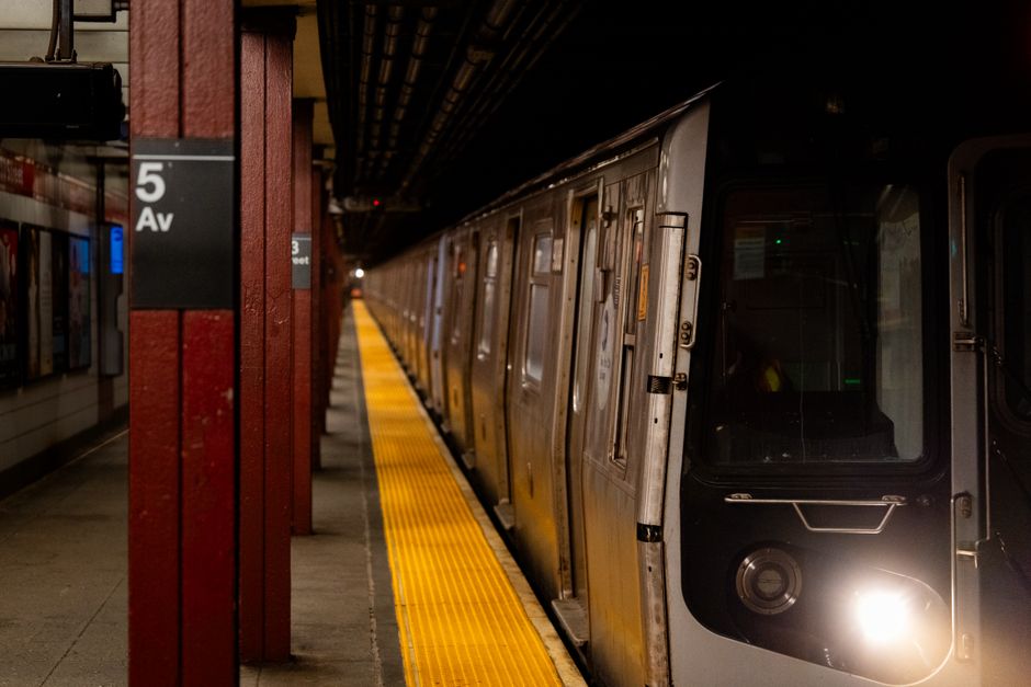 A New York City subway train arriving at a bustling station platform in the USA