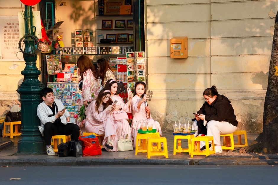 Tourist happily using a smartphone to navigate a bustling street in Hanoi, Vietnam, symbolizing easy internet access.