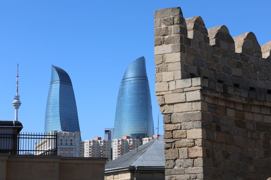 A traveler holding a travel insurance document in front of Baku Old City, Azerbaijan