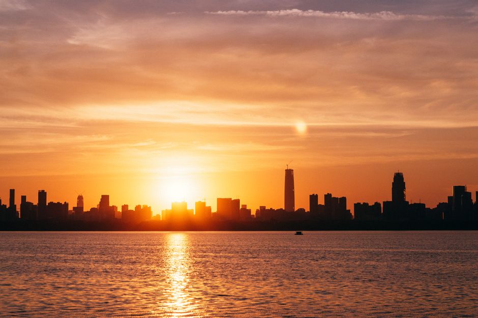 Stunning sunset over the modern Manama skyline in Bahrain, with traditional dhow boats in the foreground.