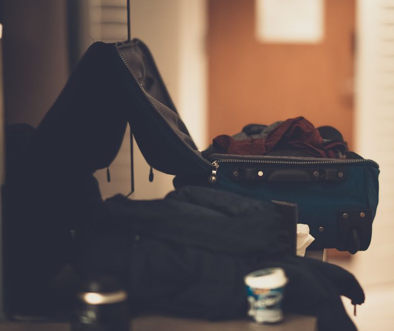 Open suitcase with lightweight summer clothes, sunscreen, and a scarf for a trip to Bahrain