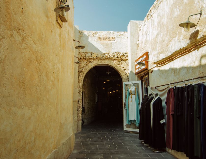 A vibrant scene at Manama Souq in Bahrain, with stalls selling various goods and shoppers browsing.