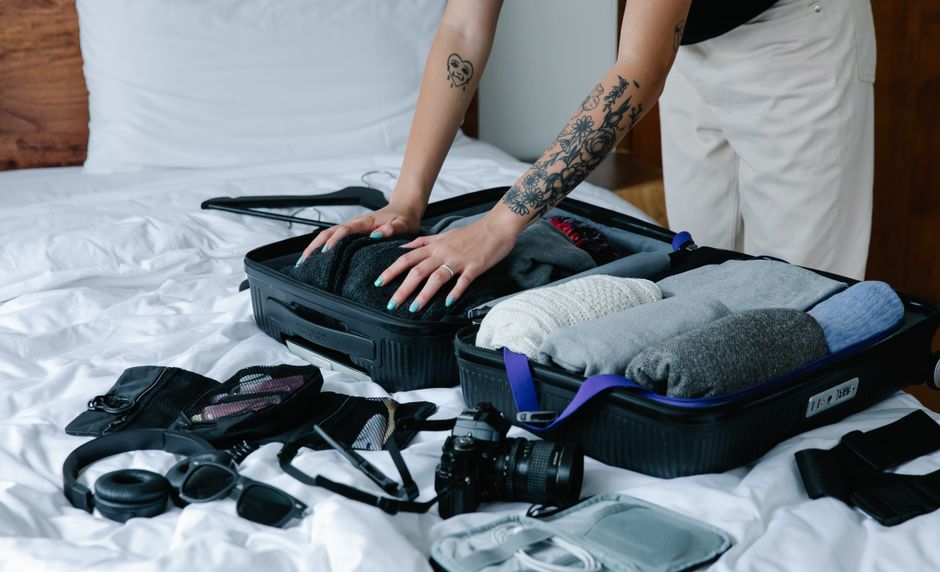 Travel suitcase with essential items for a trip to Belgium, including a power adapter, comfortable shoes, and a rain jacket