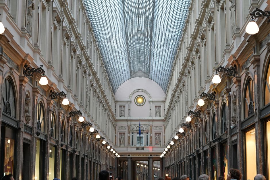 People walking along a bustling shopping street in Brussels, Belgium, with historic architecture