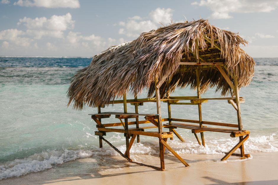 Travel essentials like sunscreen, hat, and sunglasses on a beach in the Dominican Republic