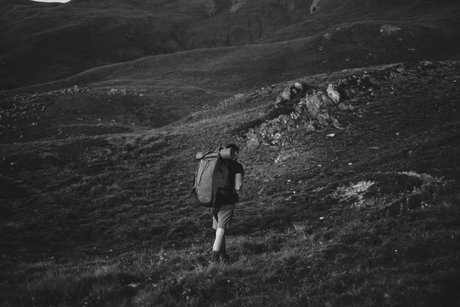 A traveler packing a backpack with a stunning Georgian mountain landscape in the background, ready for adventure.