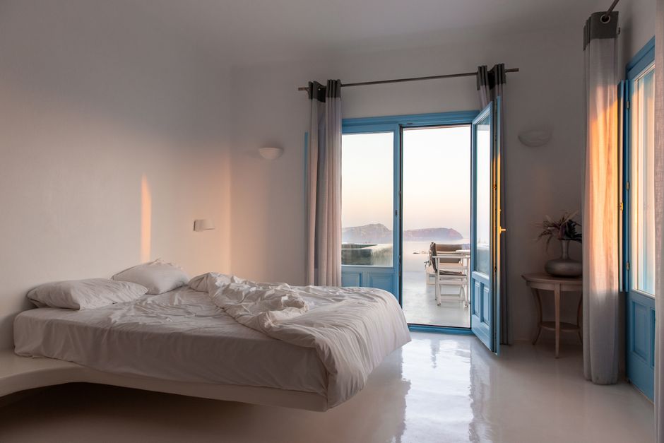 Traditional white Cycladic hotel with blue domes overlooking the Aegean Sea in Greece.