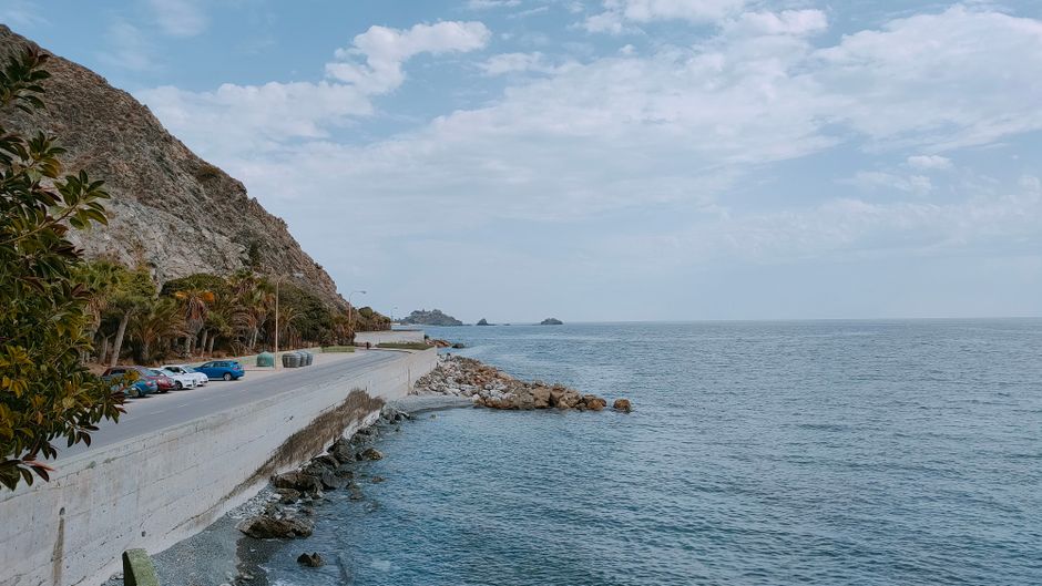 Compact rental car driving on a scenic coastal road in Greece