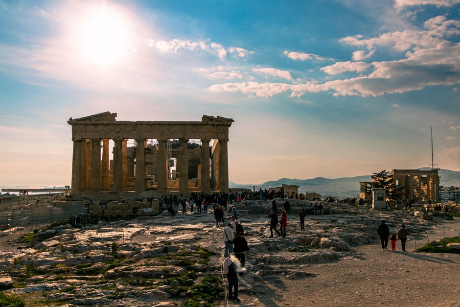 Traveler using smartphone in Athens, Greece, with the Acropolis in the distance, symbolizing easy internet access