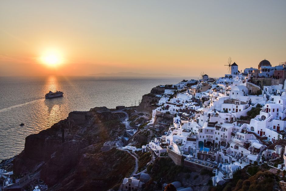 A Blue Star ferry arriving at the port of Santorini, Greece, with white-washed buildings on cliffs