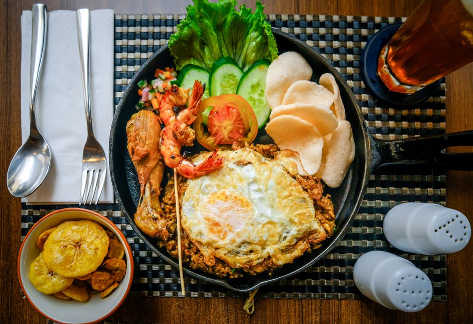 A vibrant plate of Nasi Goreng with fried egg and satay on a street food stall in Indonesia