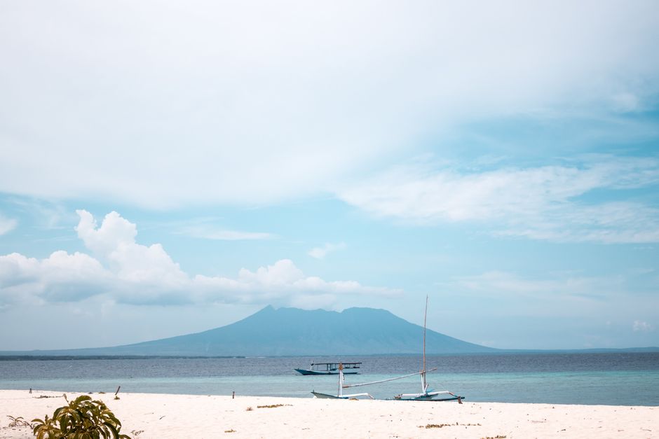 A flat lay of essential items for an Indonesia trip, including a sarong, sunscreen, and a power adapter