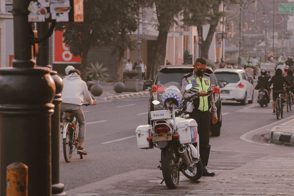 Indonesian police officer assisting a tourist in a busy street in Bali