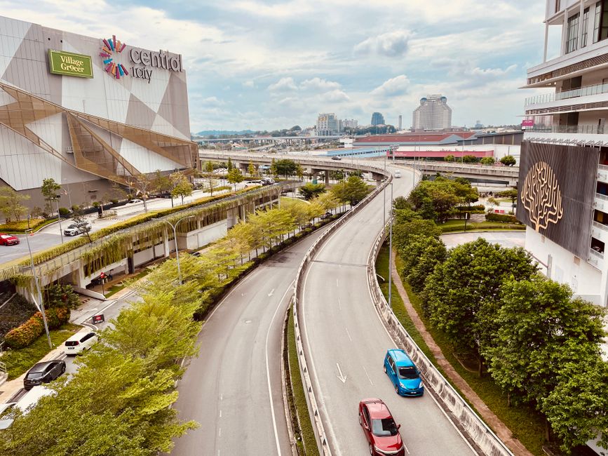 Compact rental car driving on a scenic highway in Malaysia with lush green landscape