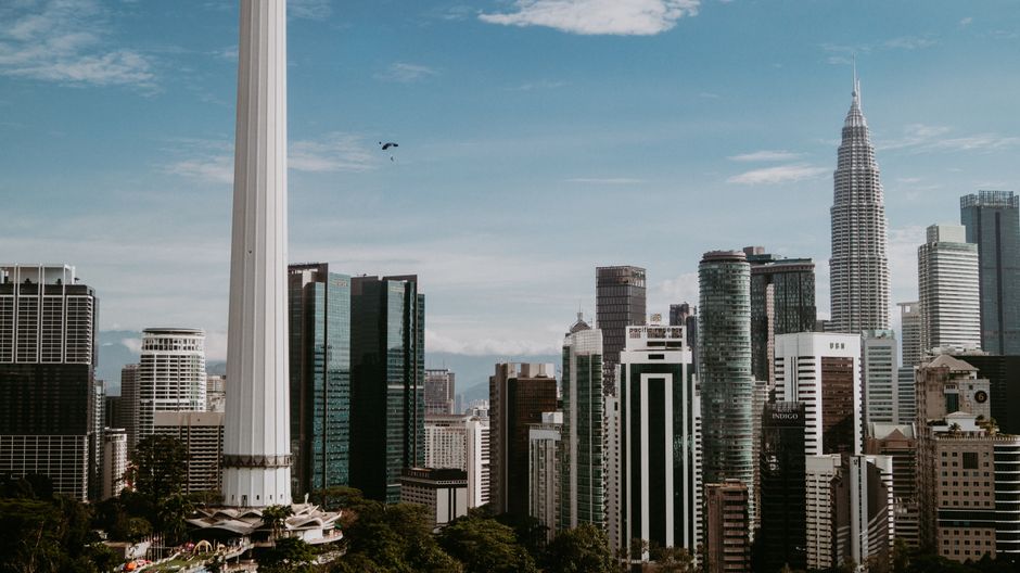 Kuala Lumpur skyline with lush green hills in the distance, hinting at nearby day trip destinations in Malaysia.