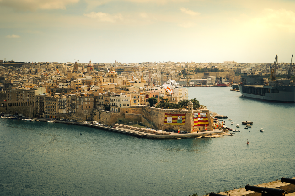 Panoramic view of Valletta, Malta at sunset, showcasing historic buildings and the harbor.