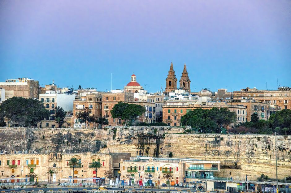 Panoramic view of Valletta, Malta at sunset, showcasing historic buildings and the harbor