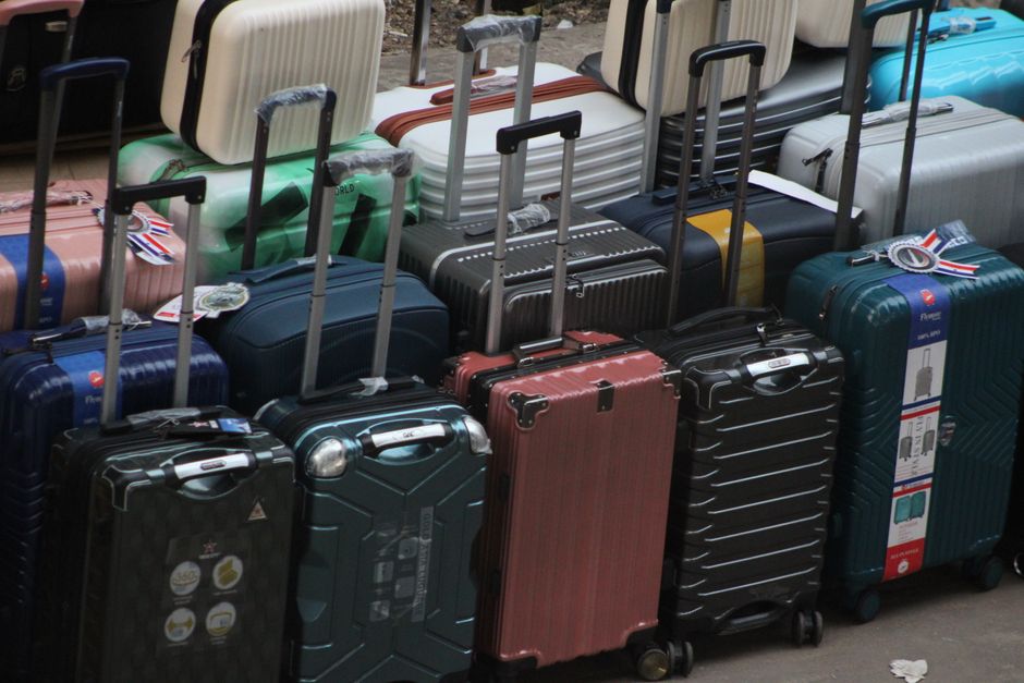 Open suitcase with summer clothes, sunscreen, and a hat for a trip to Malta
