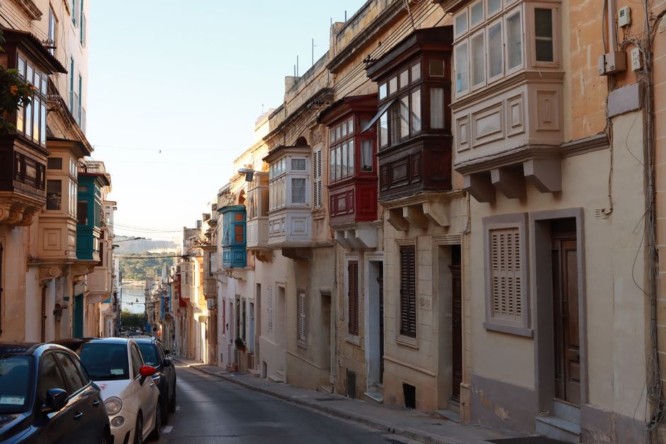 Bustling Republic Street in Valletta, Malta, with shoppers and historic buildings under a sunny sky.