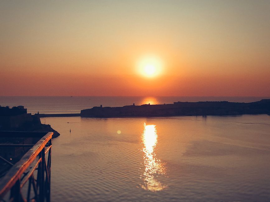 Sunset over the historic cityscape of Valletta, Malta, with the sea in the background