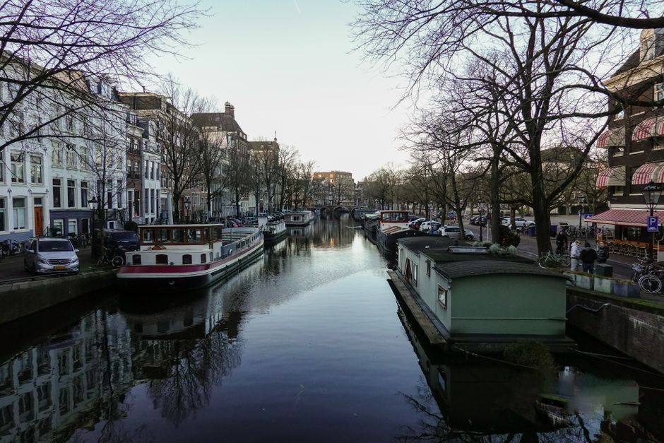 Traveler using a smartphone with a Dutch SIM card along an Amsterdam canal
