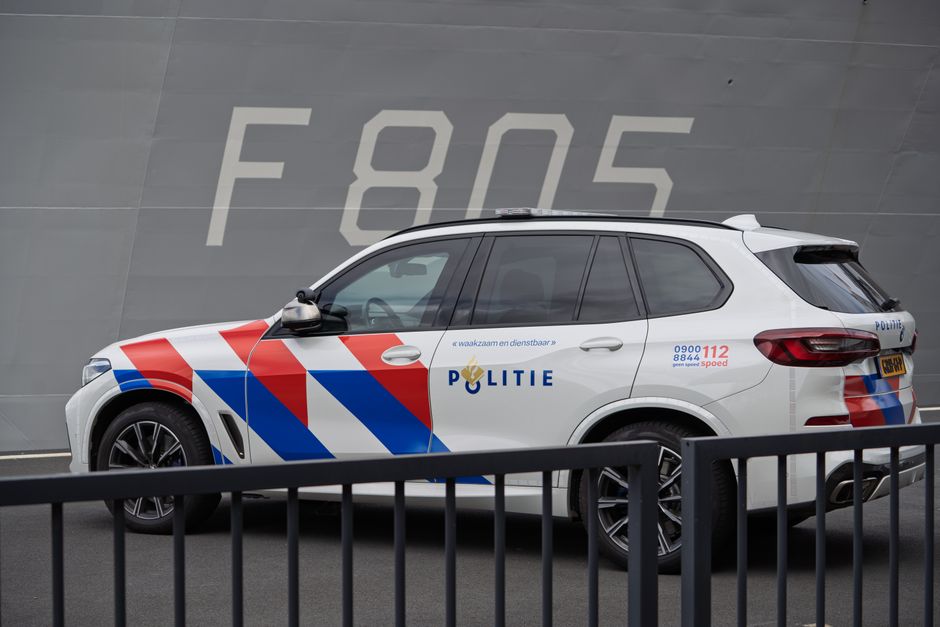 Emergency services vehicle with flashing lights in a Dutch city
