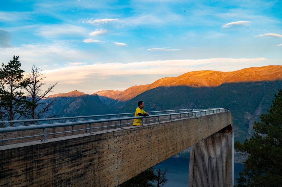 Traveler using a smartphone with a beautiful Norwegian fjord in the background, highlighting connectivity in Norway