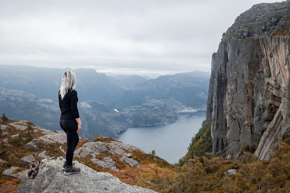 Hiker consulting a topographic map with a stunning Norwegian fjord and mountains in the background