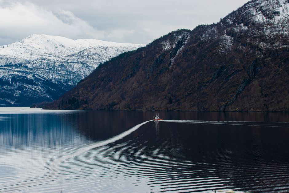 A scenic cruise boat navigating the majestic Nærøyfjord in Norway, surrounded by steep mountains and waterfalls.