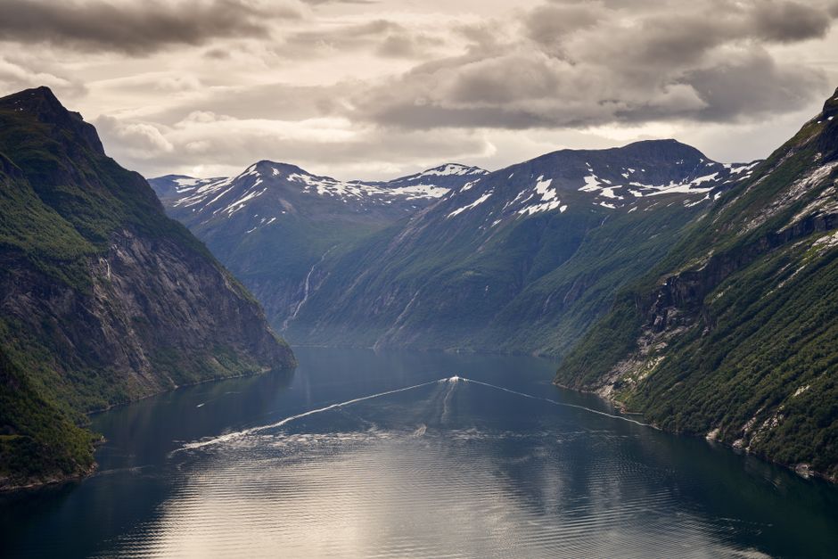 Scenic Norwegian fjord with a tour boat navigating calm waters