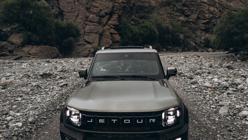 A modern SUV driving on a scenic desert road in Oman with mountains in the background