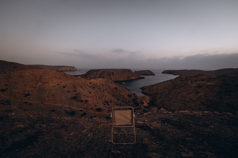 A traditional Bedouin camp set against the golden dunes of Wahiba Sands, Oman, at sunset.
