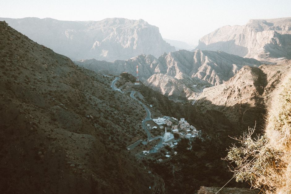 Traveler enjoying panoramic views from Jebel Shams, Oman, highlighting the need for travel insurance in adventurous settings.