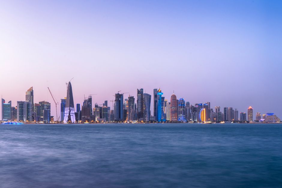 Doha skyline at sunset with traditional dhow boats in Qatar