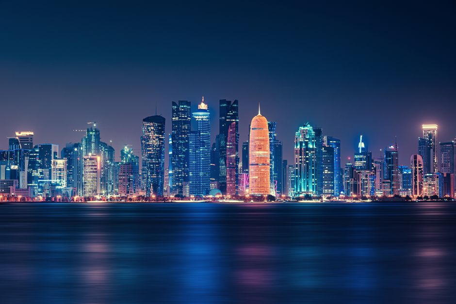 Doha skyline with modern buildings and traditional dhow boats at sunset in Qatar