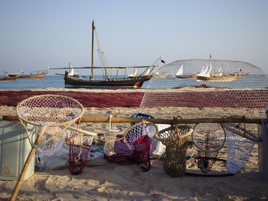 Traditional Dhow boat cruising along the modern Doha skyline in Qatar at sunset