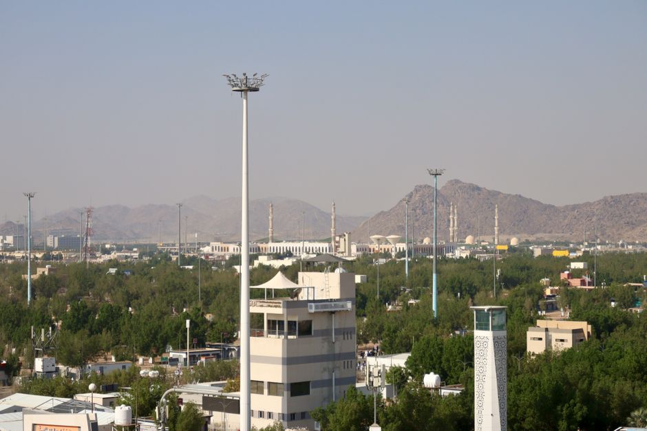 Traveler using a smartphone with Saudi Arabia's modern skyline in the background, highlighting connectivity.