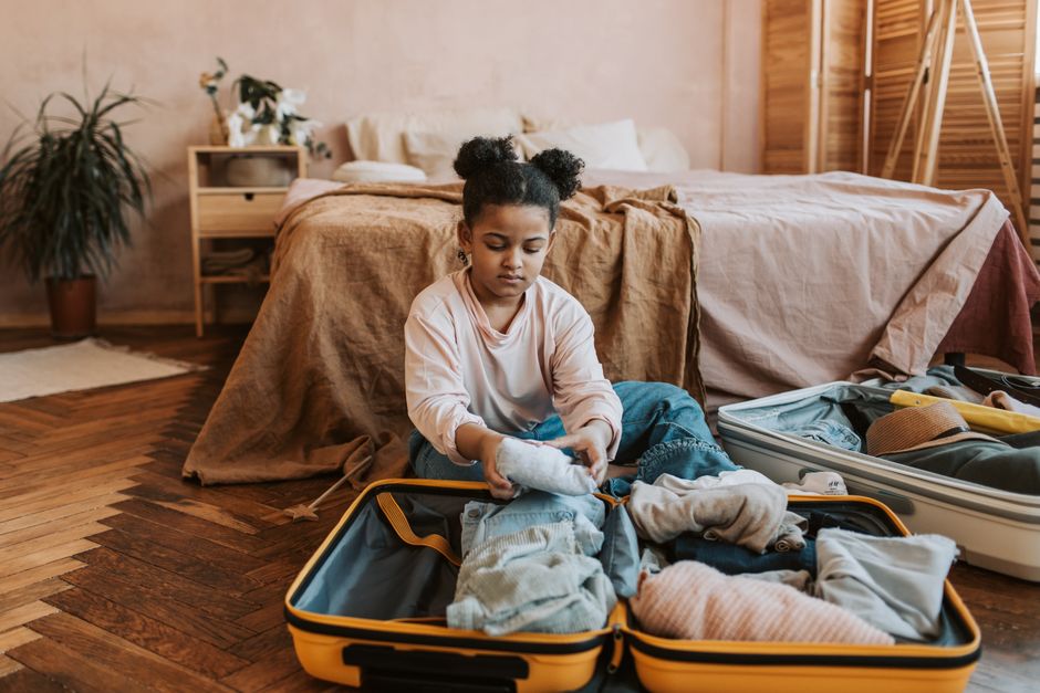A traveler organizing clothes and essentials into a suitcase for a trip to Slovakia