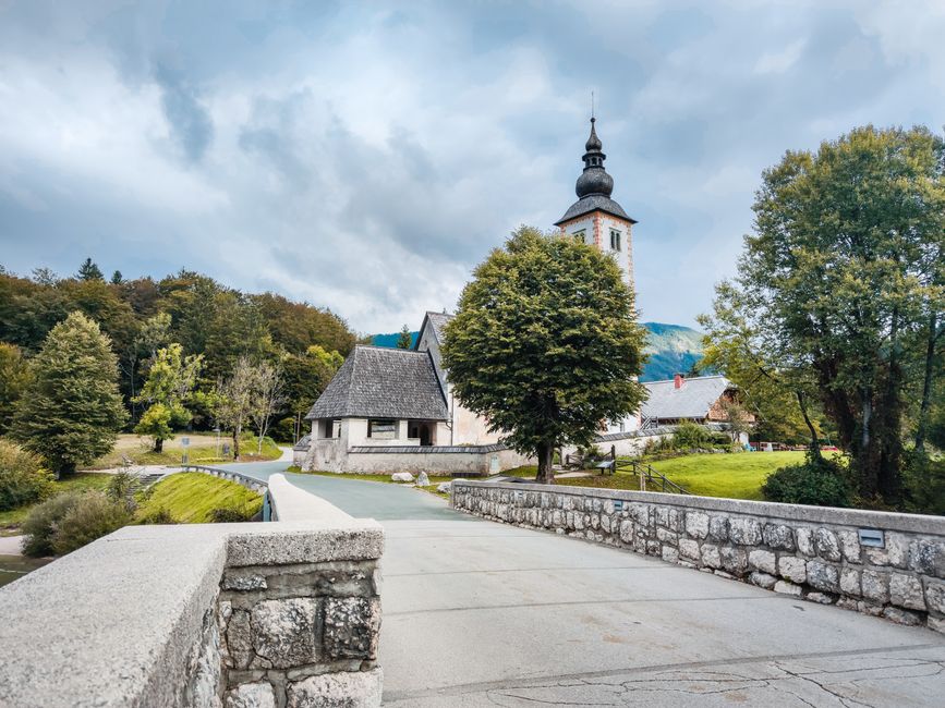 A rental car driving on a winding road through the picturesque Slovenian Alps.