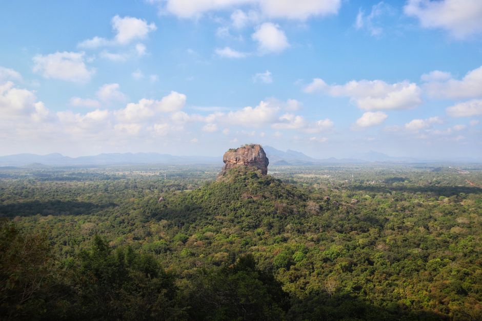 Panoramic view of Sigiriya Rock Fortress in Sri Lanka at sunrise, surrounded by lush green landscape