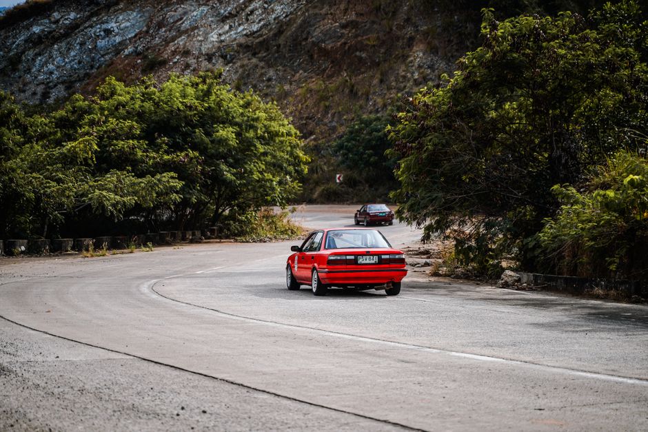 A rental car driving along a scenic coastal road in the Bahamas with turquoise water in the background.