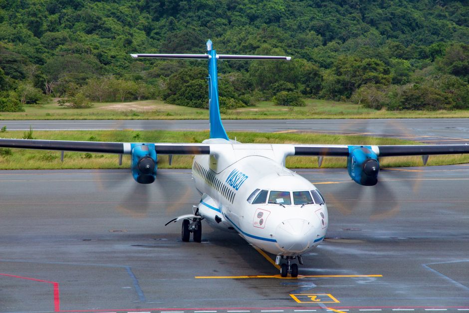 Airplane landing at Lynden Pindling International Airport in Nassau, Bahamas, with turquoise waters in the background