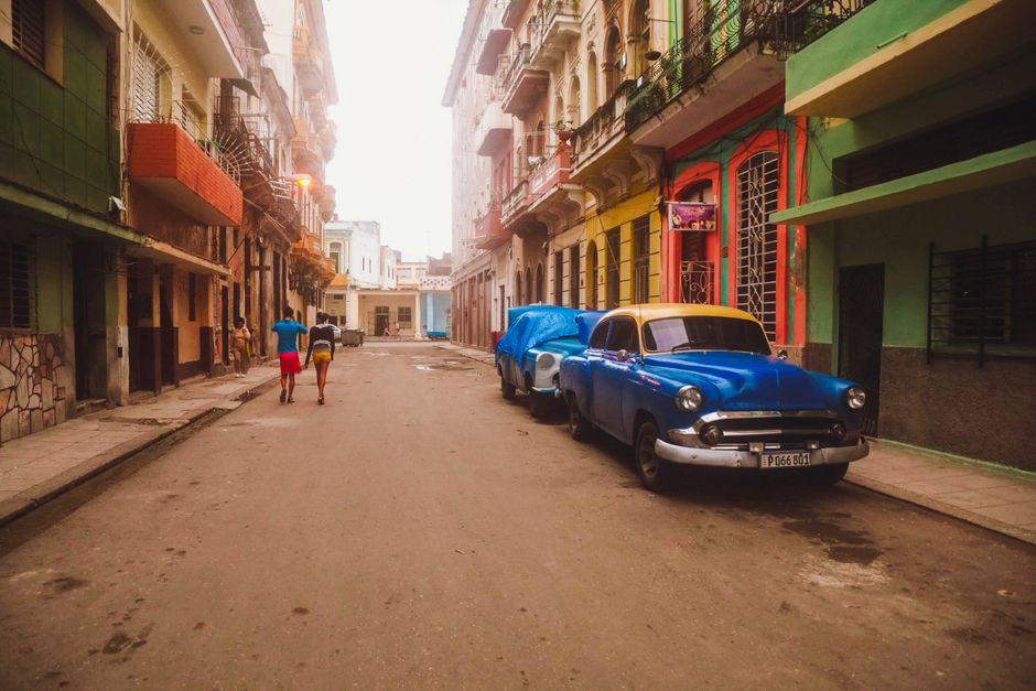 Colorful classic American car driving down a vibrant street in Old Havana, Cuba