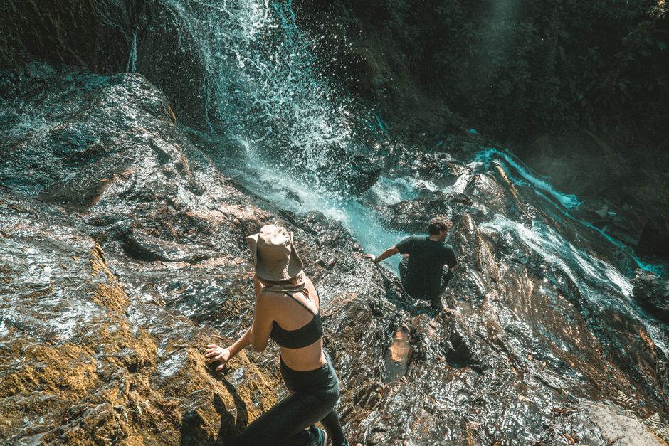 Tourists climbing the terraced rocks of Dunn's River Falls in Jamaica, surrounded by lush tropical greenery