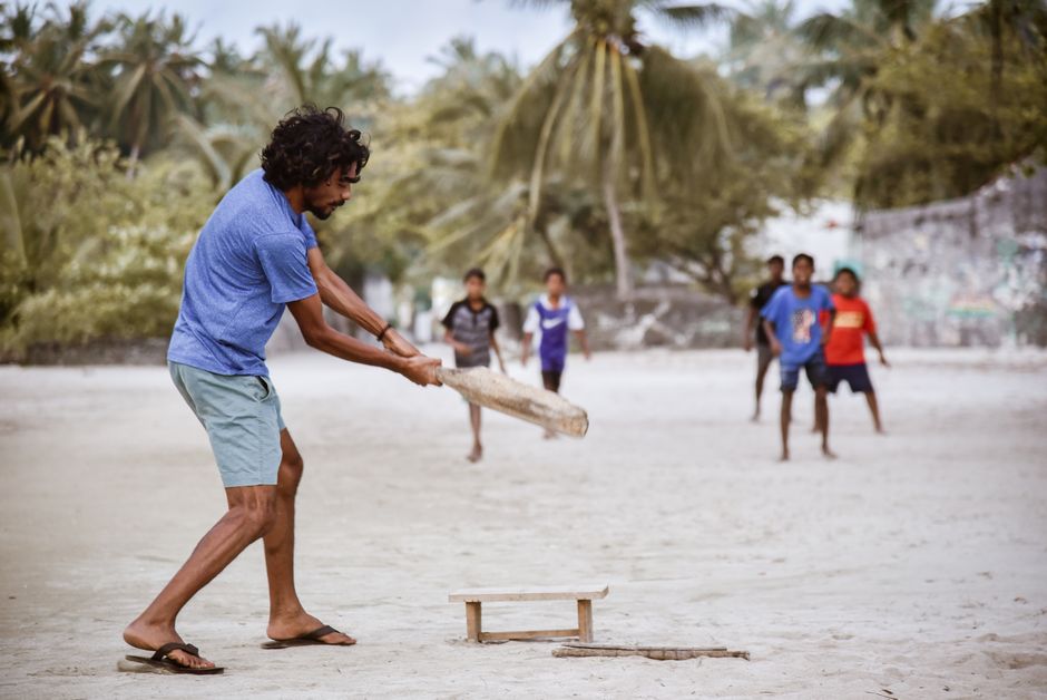 A charming guesthouse on a local island in the Maldives, with palm trees and a pristine beach.