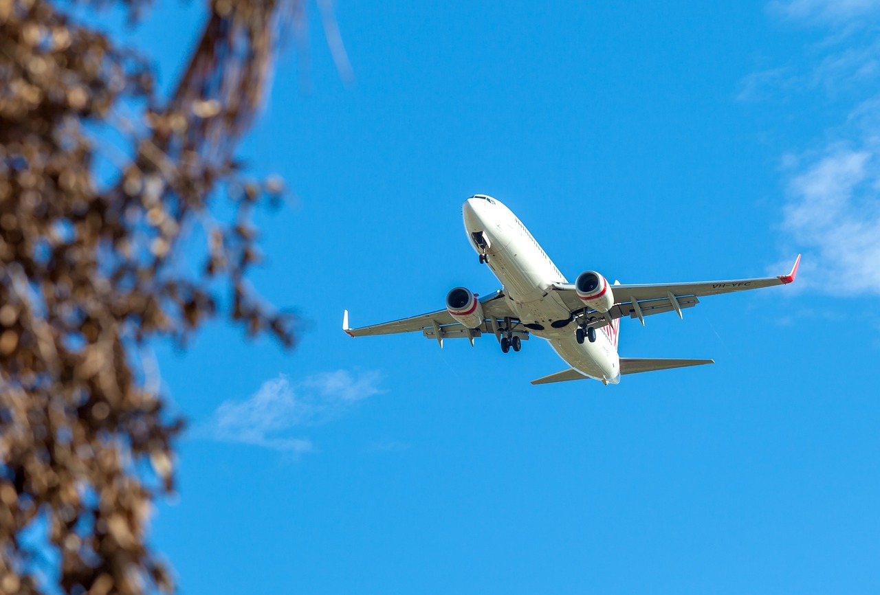 An airplane landing at Velana International Airport in the Maldives with turquoise waters and islands in the background