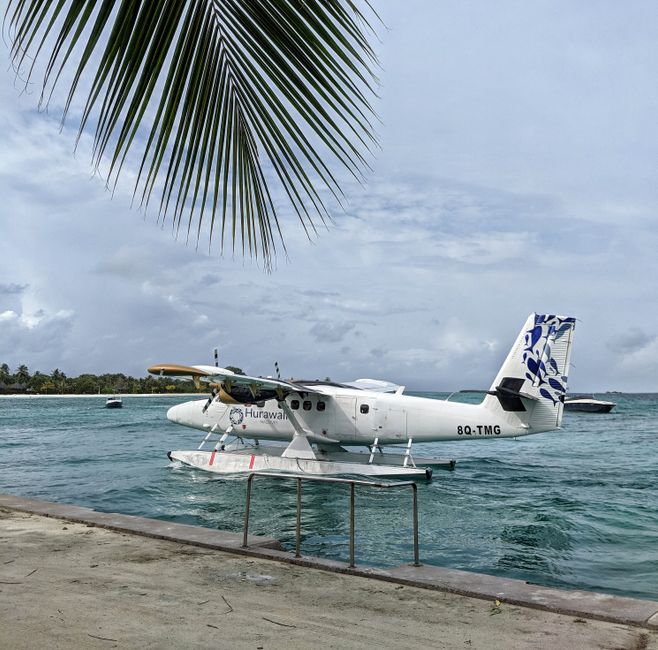 Seaplane flying over a stunning turquoise lagoon in the Maldives, transporting travelers to an island resort.