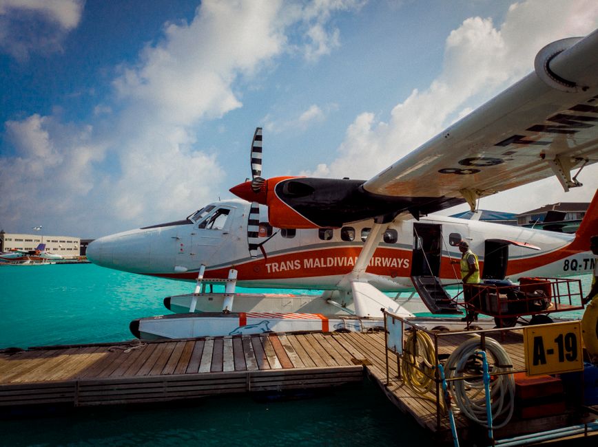 A seaplane taking off from turquoise waters in the Maldives, heading towards a luxury resort