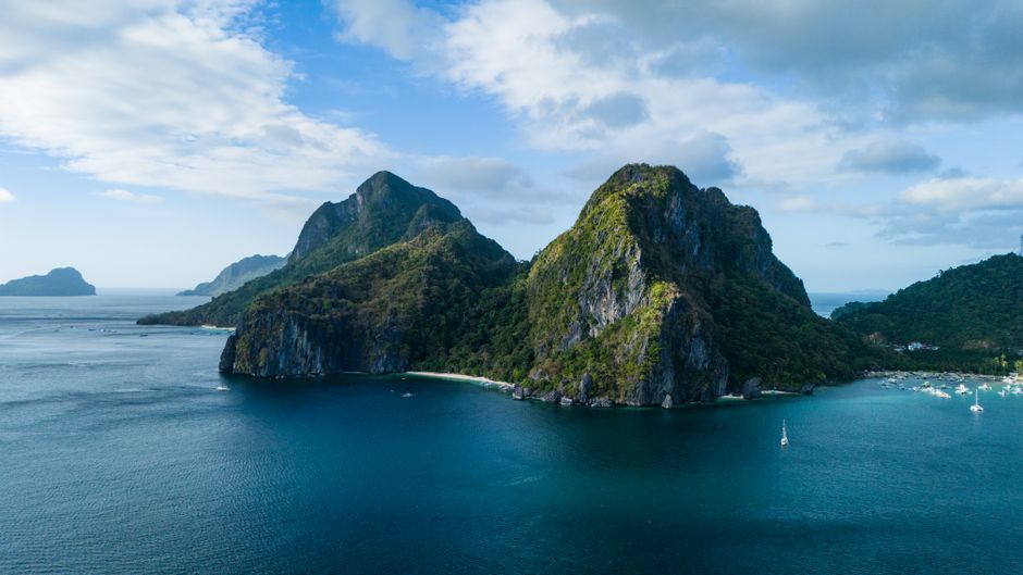 Tourists enjoying island hopping in El Nido, Palawan, Philippines with limestone cliffs and clear blue water