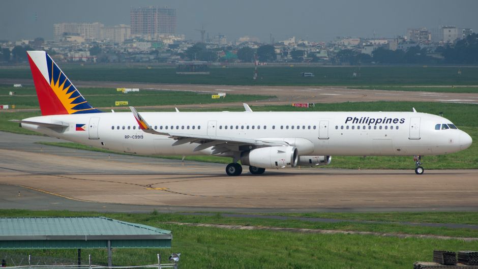 Passengers waiting in a modern airport terminal in the Philippines due to a flight delay